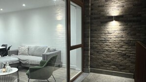 A modern living room with a stone accent wall, a glass door, and a cozy seating area. - Riverside Retreat in Barking (Barking)