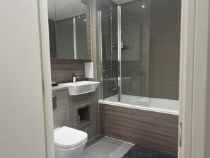 A modern bathroom with a glass-enclosed shower, a white sink, and a toilet. - Riverside Retreat in Barking (Barking)