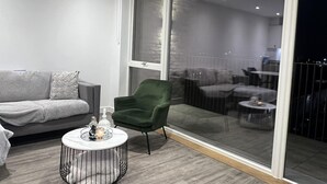 A modern living room with a grey sofa, a green armchair, and a round coffee table with candles. - Riverside Retreat in Barking (Barking)