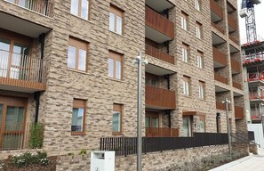 A multi-story residential building with brick facade, balconies, and a gated entrance. - Riverside Retreat in Barking (Barking)