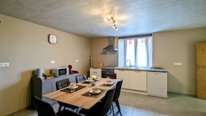 Cocina compacta con zona de comedor, un reloj en la pared y ventana que deja entrar luz natural.