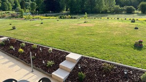 Un jardín ajardinado con un sendero pavimentado, una fuente ornamental y diversas plantas.