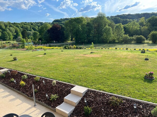 A landscaped garden with a paved walkway, a small water feature, and a variety of plants.