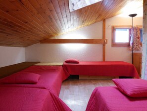 Una habitación con dos camas, vigas de madera en el techo, una ventana con cortinas y un armario de madera.