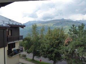 Un edificio con balcón que da a un paisaje montañoso.