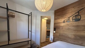 A bedroom with a bunk bed, a wooden wall with a ski lift mural, and a hanging light fixture.