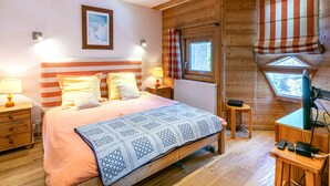 A cozy bedroom with a bed, bedside lamps, a window with a view, and a small desk with a chair. - Charming apartment with wifi, ski-in/ski-out in Val-d'Isère (Val-d'Isère)