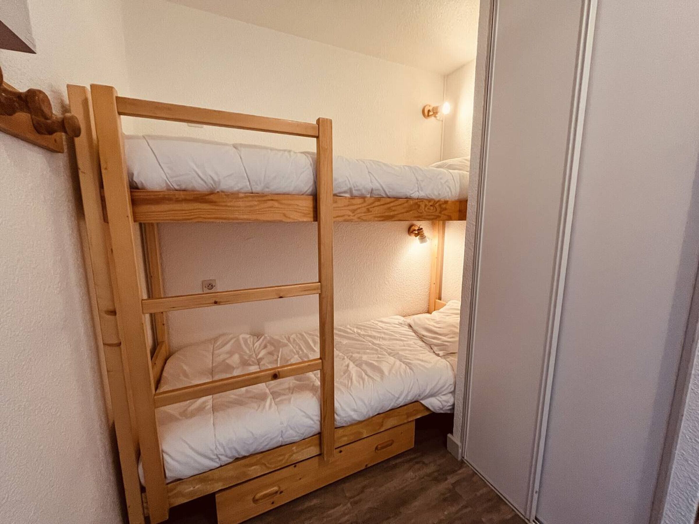A bunk bed with two levels, each with a pillow and a light fixture above.