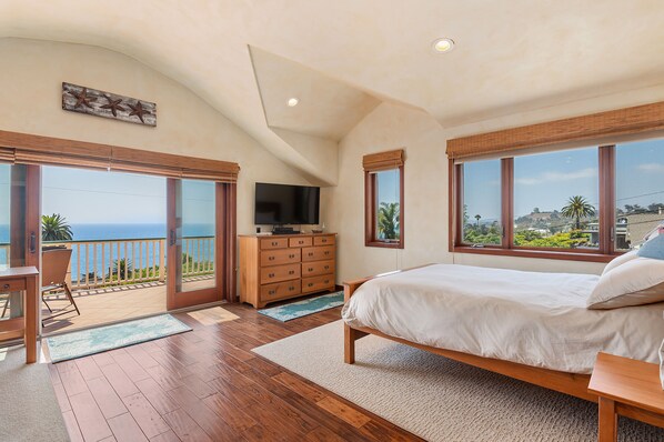 Enjoy a serene ocean view from the comfort of this spacious bedroom with a large bed, flat-screen TV, and cozy seating area.