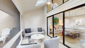 Um interior moderno com um conjunto de sofás, uma mesa de centro redonda e uma porta de vidro que dá para uma cozinha.