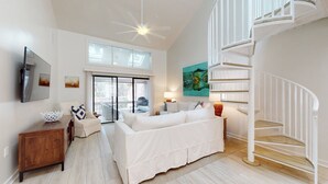 Uma sala de estar moderna com um sofá branco, um armário de madeira, uma televisão e uma escada em espiral.