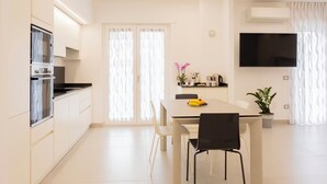 Une cuisine moderne avec des meubles blancs, un plan de travail noir et un coin repas comprenant une table et des chaises.