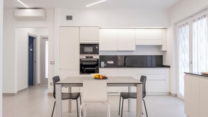Une cuisine moderne avec des meubles blancs, un plan de travail noir et un coin repas comprenant une table et des chaises.