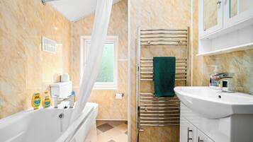 Huis | Badkamer | Een bad/douchecombinatie, een diep bad, een haardroger, handdoeken