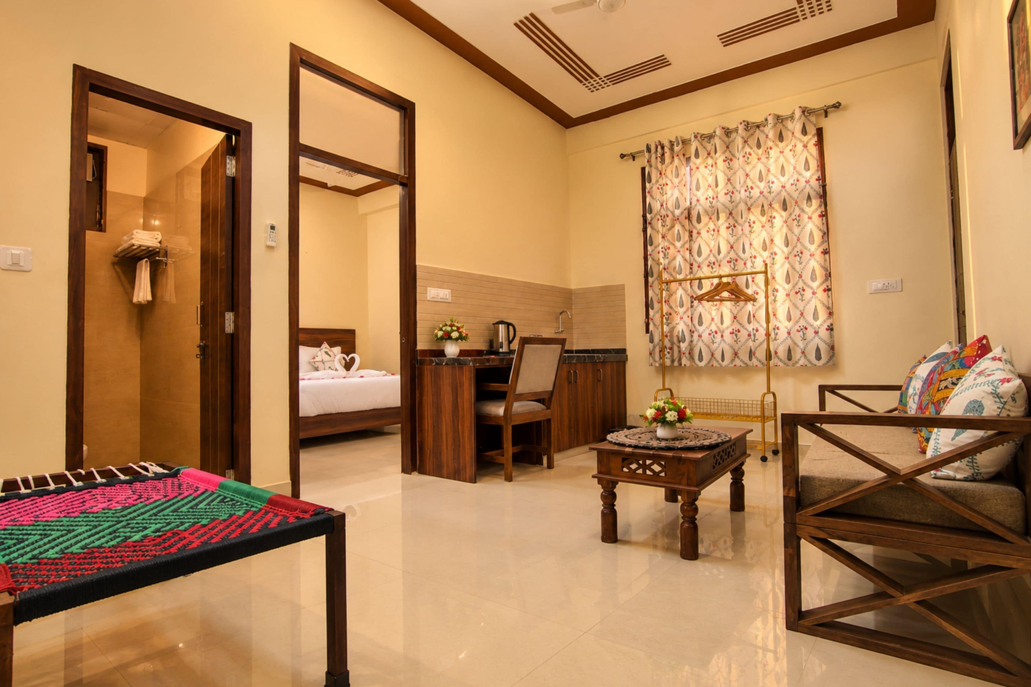 A hotel room with a bed, a desk, a chair, a table, and a sofa.