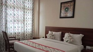 A bedroom with a large bed, a wooden headboard, and a chair. - Vidhus Lado Home Ranthambhore (Sawai Madhopur)