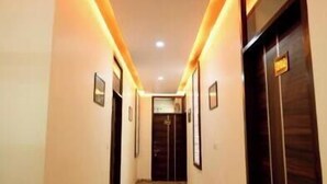 A hotel hallway with patterned carpet, wooden doors, and warm lighting. - Vidhus Lado Home Ranthambhore (Sawai Madhopur)