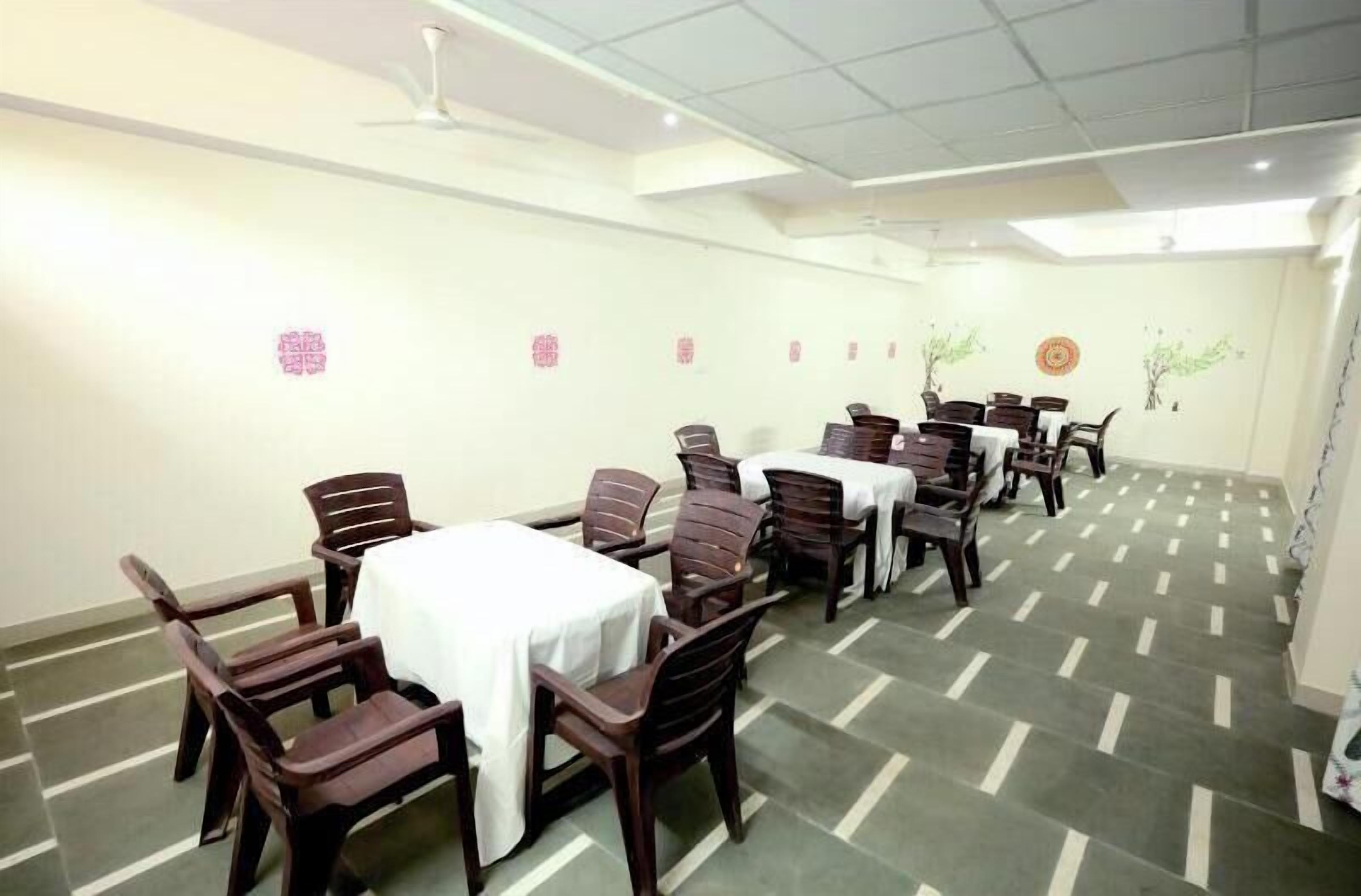 Une salle de conférence dotée de plusieurs tables et chaises, de nappes blanches et d’éléments décoratifs muraux.