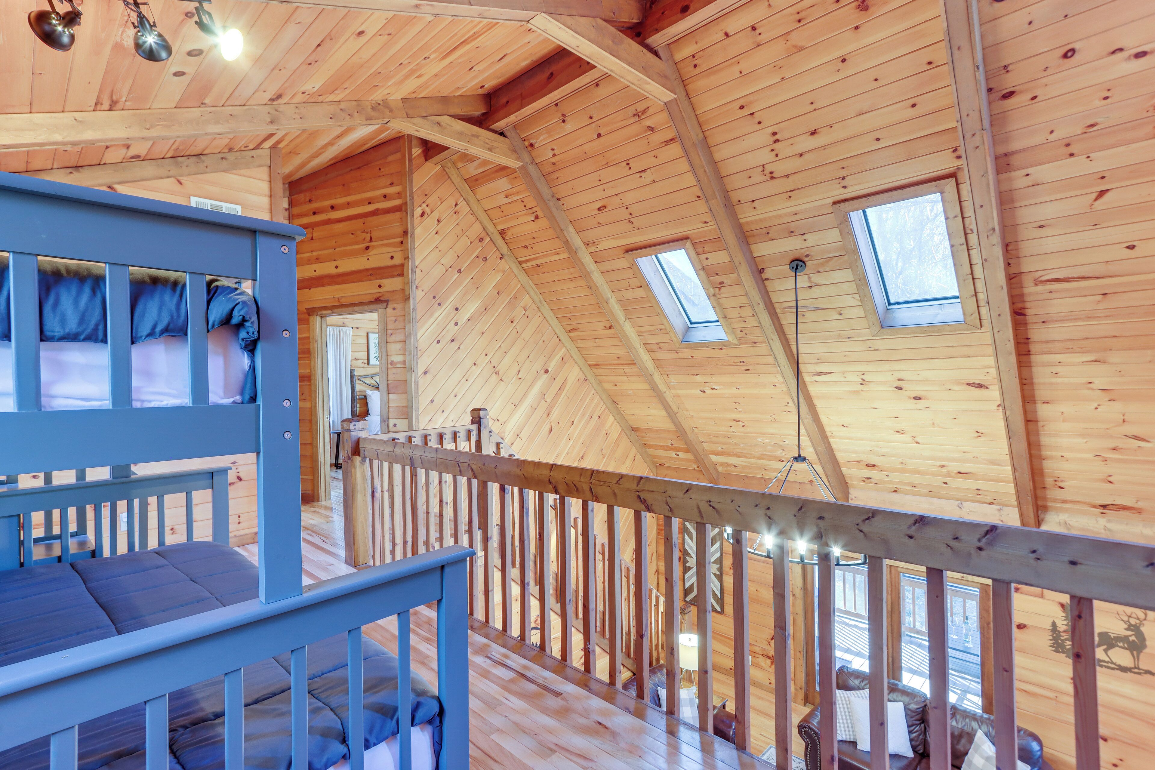 L’intérieur d’une cabane en bois, avec un lit superposé, un escalier et une mezzanine dotée d’une fenêtre.