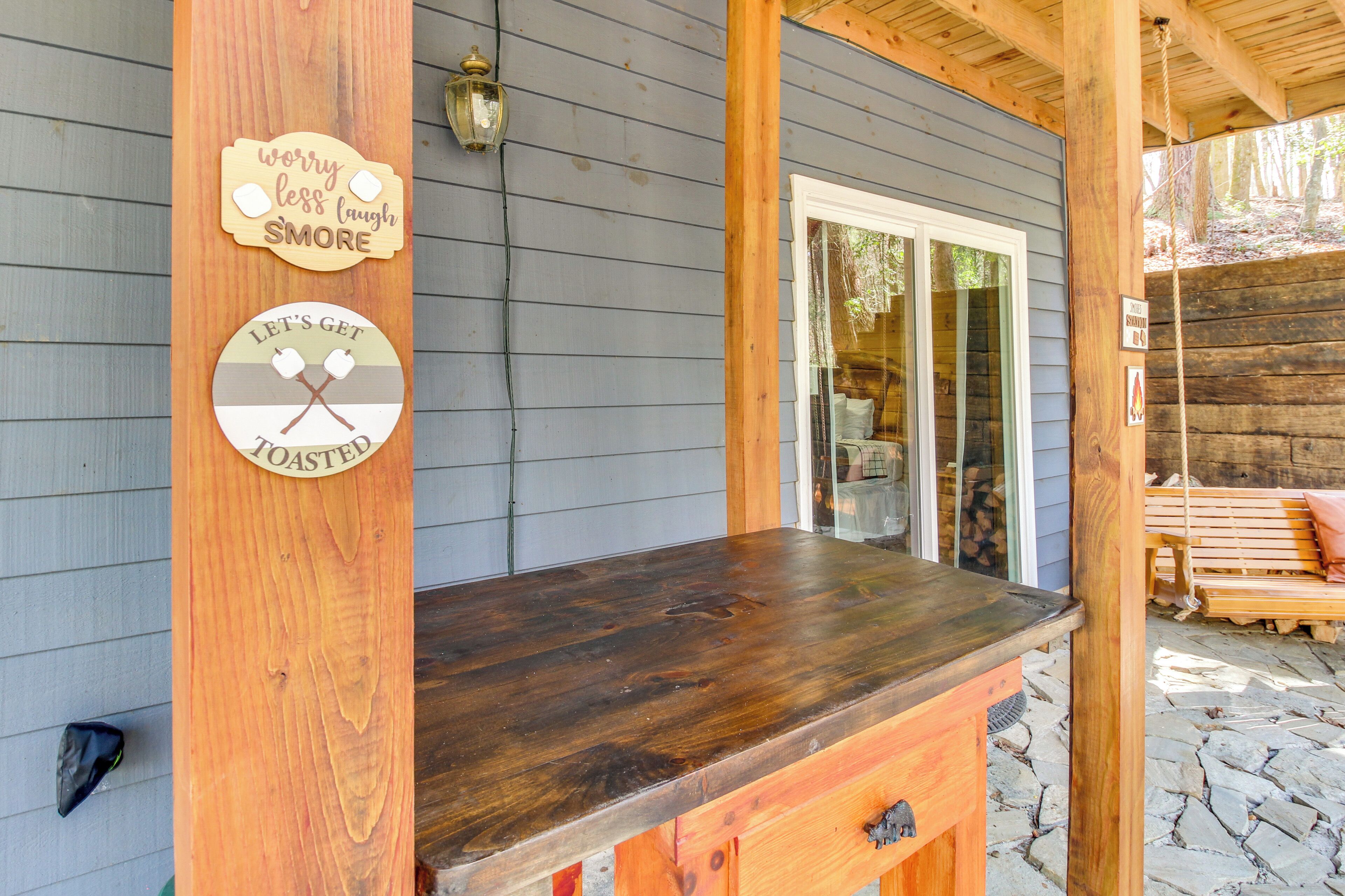 An outdoor wooden bar with a sign that reads "worry less laugh more" and another sign that says "Let's get toasted."