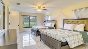 A bedroom with two beds, a ceiling fan, a window with blinds, and a door. - 11 Mi to Dtwn: Ocala Home w/ Screened-in Lanai! (Ocala)