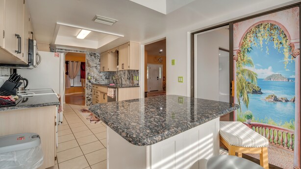 A modern kitchen with granite countertops, a built-in oven, and a view of the sea through a large window. - 11 Mi to Dtwn: Ocala Home w/ Screened-in Lanai! (Ocala)