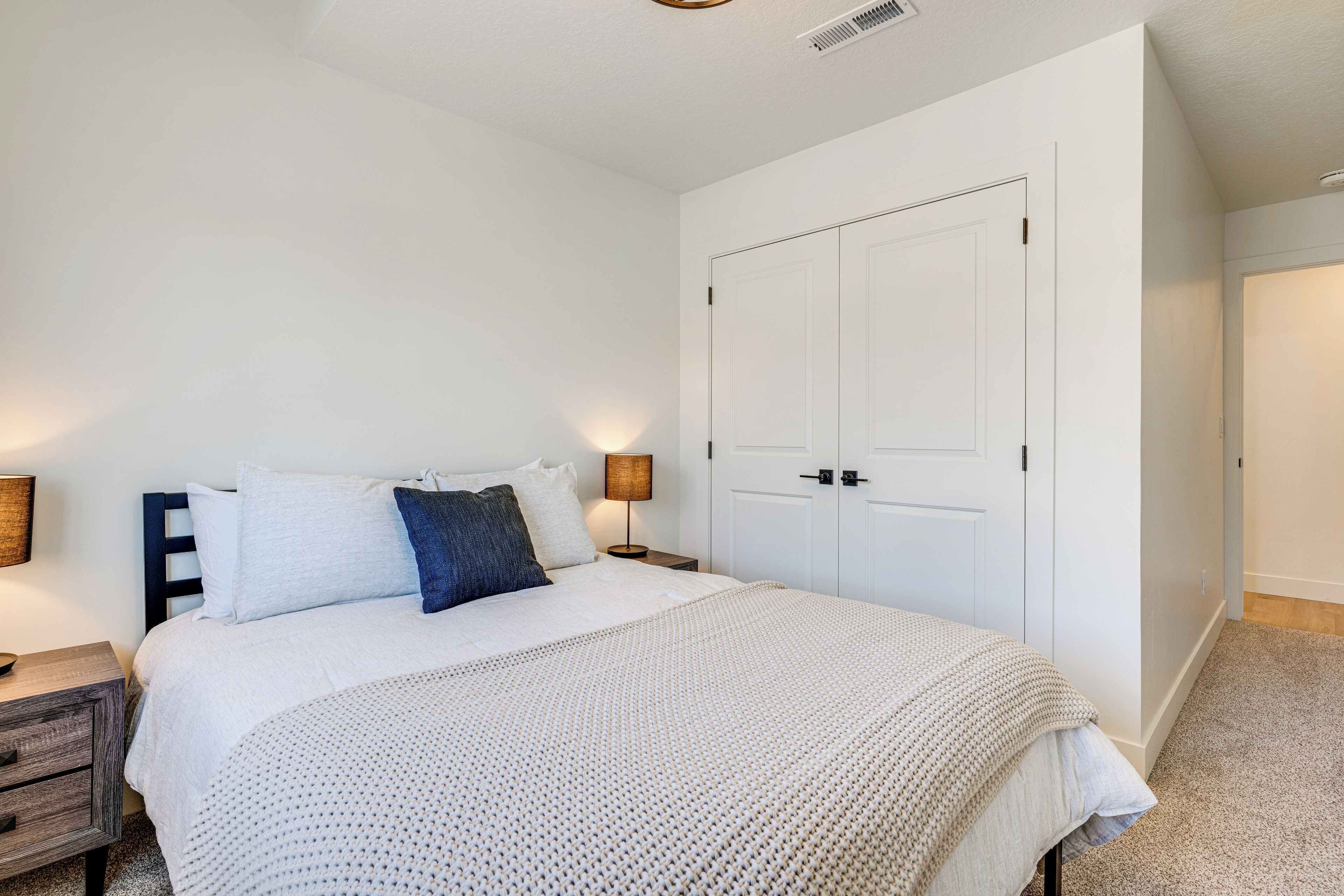 Un dormitorio con cama, mesitas de noche, armario y lámpara.