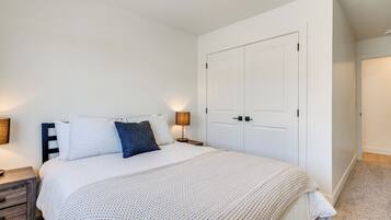 Un dormitorio con cama, mesitas de noche, armario y lámpara.
