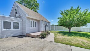 A single-story house with a front porch, a small garden, and a tree in the yard.