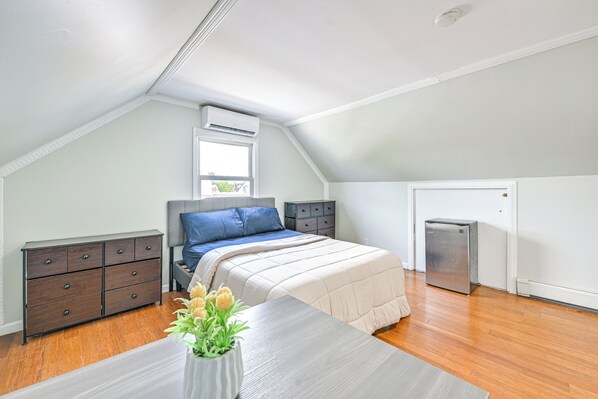 A bedroom with a bed, dresser, and a small refrigerator. - Long Island Duplex By Airport & Train (Valley Stream)