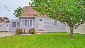 A single-story house with a front door, two windows, and a small front yard with grass and a tree.