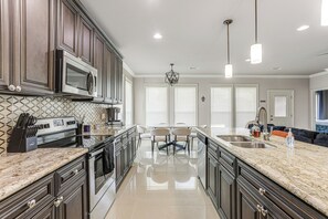 A modern kitchen with dark wood cabinets, stainless steel appliances, and a marble countertop. - Arabi Home w/ Deck: 7 Mi to Downtown New Orleans! (Arabi)