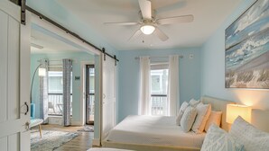 Un dormitorio con dos camas, un ventilador de techo y un cuadro en la pared.