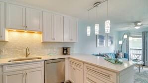 Una cocina moderna con armarios blancos, lavavajillas e iluminación colgante.