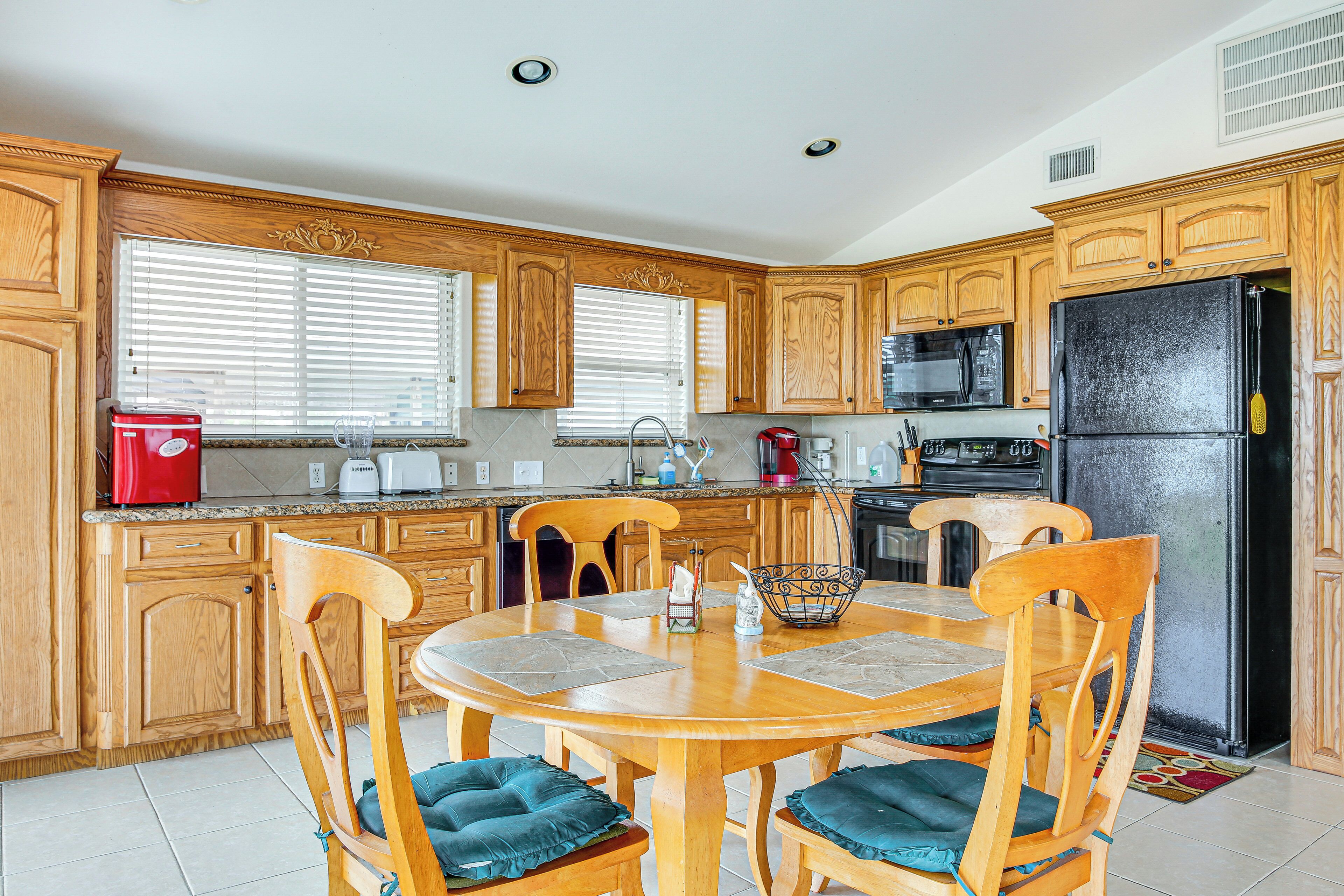 A kitchen with wooden cabinets, a dining table with chairs, a refrigerator, and a microwave.