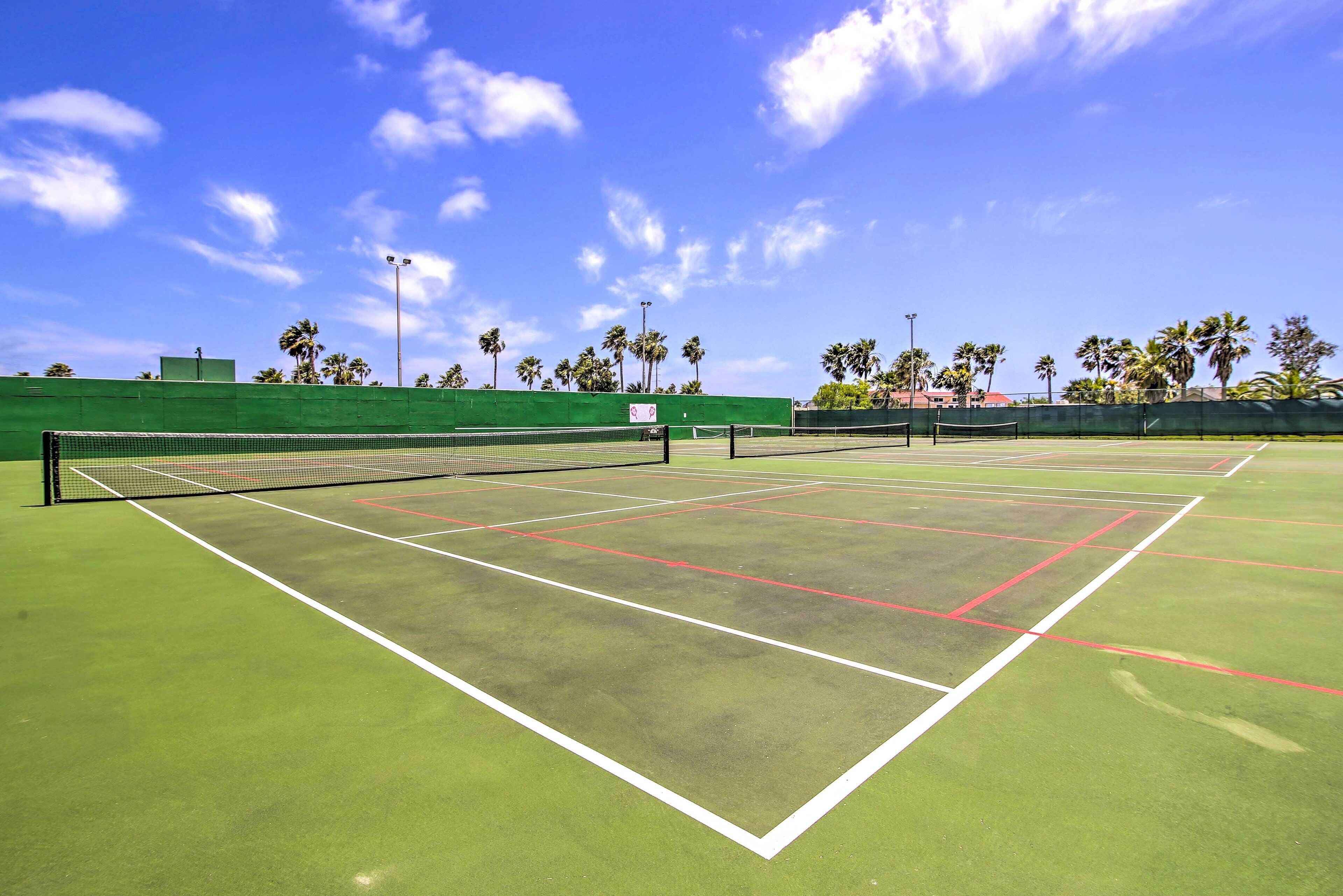 A tennis court with green flooring, white boundary lines, and a net.