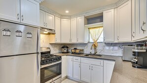 A kitchen with white cabinets, a stainless steel refrigerator, a stove, and a sink. - Pet-friendly Valley Stream Duplex - 1 Mi to Mall! (Valley Stream)