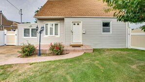 A single-story house with a front porch, a small front yard, and a garage. - Pet-friendly Valley Stream Duplex - 1 Mi to Mall! (Valley Stream)