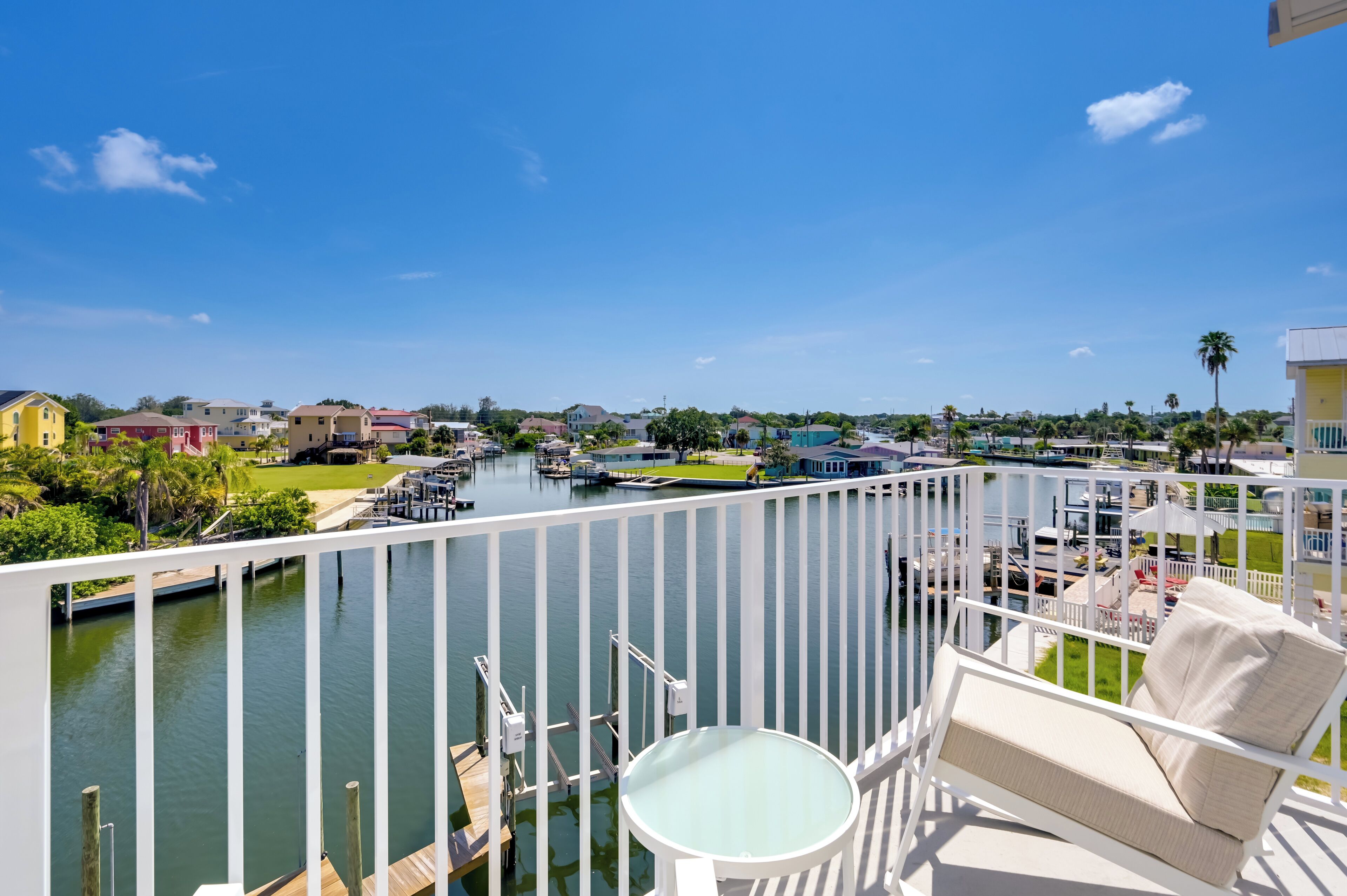 A balcony with a view of a marina, docked boats, and a clear blue sky.