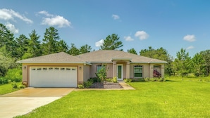 A single-story house with a garage, a front lawn, and a small garden area. - 5 Mi to Weeki Wachee Springs! Poolside Retreat (Brooksville)
