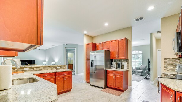 A spacious kitchen with granite countertops, stainless steel appliances, and wooden cabinets. - 5 Mi to Weeki Wachee Springs! Poolside Retreat (Brooksville)