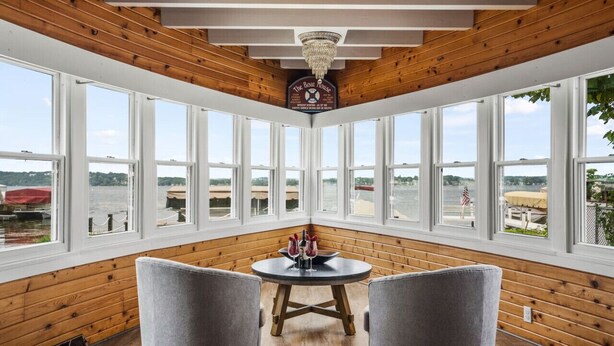 A room with large windows, a wooden ceiling, and a table with chairs.
