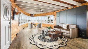 A spacious room with a wooden ceiling, large windows, a sofa, and a coffee table.