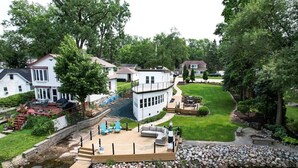 A lakeside property with a dock, a boat house, and a well-maintained lawn.