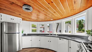 A modern kitchen with white cabinets, a stainless steel refrigerator, and a curved countertop.