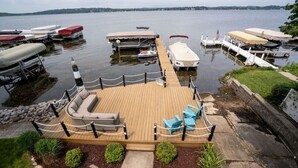 A docked boat with a covered seating area, a small dock, and a grassy area with a pathway leading to the dock.