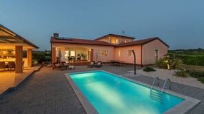 A residential property with a swimming pool, outdoor seating area, and a covered patio.