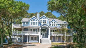 A large, two-story house with a front porch, multiple windows, and a covered front entrance. - 12BR Retreat w/ Private Pool, Theater, Volleyball + Elevator | Perfect for Large Groups (Corolla)