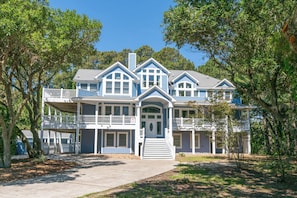 A large, two-story house with a front porch, multiple windows, and a covered front entrance.