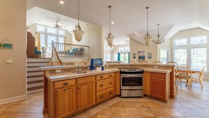 A spacious kitchen with wooden cabinets, a stainless steel oven, and a large island. - 12BR Retreat w/ Private Pool, Theater, Volleyball + Elevator | Perfect for Large Groups (Corolla)